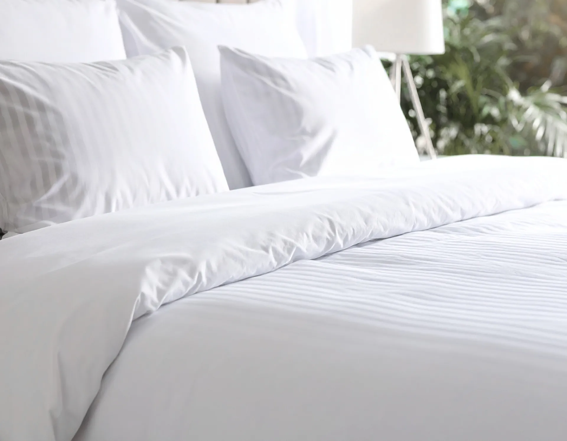 Lit fait avec du linge hôtelier blanc à bande satinée